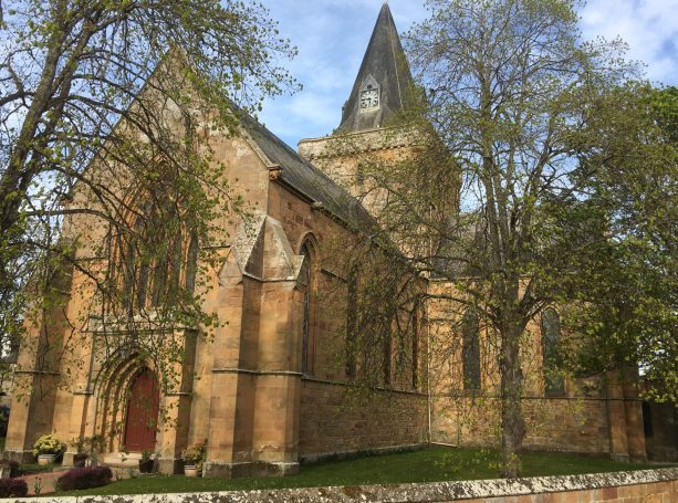 Dornoch Cathedral in the Scottish Highlands, historic stone church under blue sky